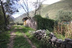 a stone building next to a stone wall next to a mountain at House for 3 people in Urubamba in Urubamba