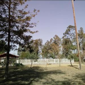a park with trees and a fence in the background at Finca Huallpamarjka in Salta +6 photos