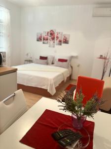 Zimmer mit einem Bett und einem Tisch mit einem roten Stuhl in der Unterkunft Apartments Ivana Bibinje in Bibinje