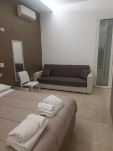 1 dormitorio con sofá y 1 cama con toallas. en Villa Matilde Monteroni, en Monteroni di Lecce