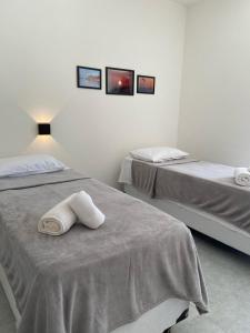 two beds in a white room with towels on the bed at Marbello Pousada Gostoso in São Miguel do Gostoso