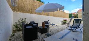a patio with chairs and an umbrella and a table at Superbe Maison Loft 80 m2 au calme avec jardin et parking privés proche Paris Disney la vallée village in Fontenay-sous-Bois