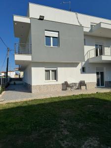 a house with two chairs in front of it at Adoniss Apartmentss in Paralia Dionysiou