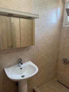 a bathroom with a sink and a mirror at Adoniss Apartmentss in Paralia Dionysiou