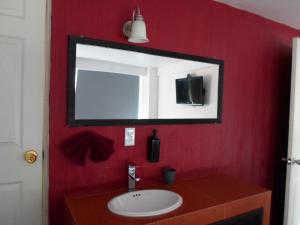 Baño rojo con lavabo y espejo en Hotel María Bonita, en Tlaxcala de Xicohténcatl