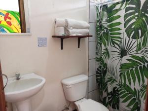 ein Badezimmer mit einem Waschbecken, einem WC und einem Duschvorhang in der Unterkunft MisMiriam in Tortuguero