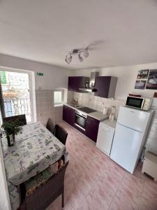 a kitchen with a table and a white refrigerator at Apartments Tudor Nikola in Hvar +25 photos