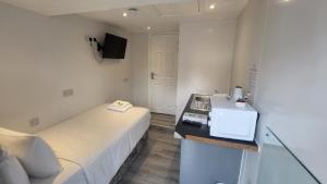 um pequeno quarto branco com uma cama e um lavatório em Nysdill Hotel Norwich em Norwich