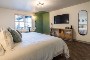 a bedroom with a large white bed with a flat screen tv at The Local Motel & Shops in Eugene