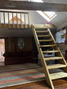 Cama elevada con escaleras en habitación con sofá en Quirky Barn Conversion Crowhurst Battle, en Crowhurst