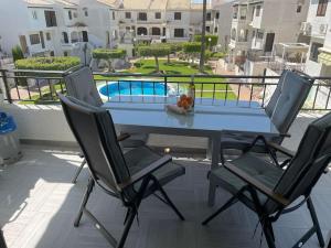 a table and chairs on a balcony with a pool at Hidden Gem Playa Flamenca Apartment with Pool View - Oleza Garden in Playa Flamenca