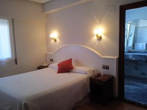Hotel Sablón في يانس: غرفة نوم عليها سرير ومخدة حمراء