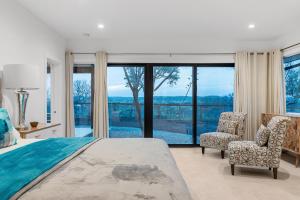 a bedroom with a bed and a chair and windows at Guadalupe Bluff Modern House in Kerrville