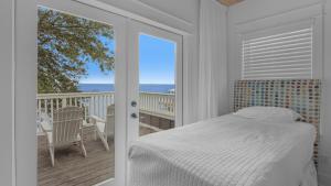 Un dormitorio con una cama y un balcón con vista al mar. en Dock of the Bay, en Santa Rosa Beach
