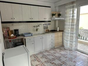 eine Küche mit weißen Schränken und einem großen Fenster in der Unterkunft Nancy & Vaggelis Holiday Studios in Litochoro