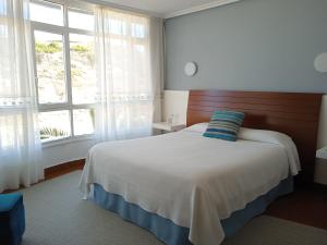 a bedroom with a bed and a large window at Hotel Sablón in Llanes