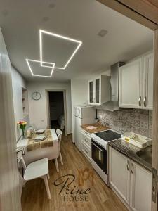 a kitchen with white cabinets and a table with a dining room at Princ house in Leskovac