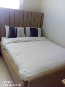 a bed with white sheets and blue pillows at Top tier A 01 in Nakuru