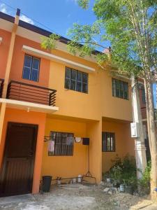Una casa naranja con garaje y un árbol. en 2 Bedroom House in Camella Carcar Cebu, en Guinauayan