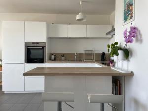 a kitchen with white cabinets and a counter with purple flowers at T2 soleil et mer in Bandol