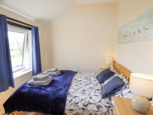 a bedroom with a bed with blue sheets and a window at Hillview in Colwyn Bay