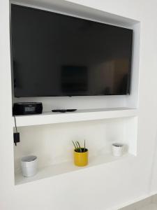 uma televisão de ecrã plano numa parede branca com três chávenas em Posada Centric Studio Isla Verde em San Juan