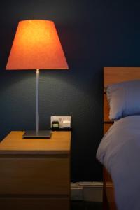 a lamp on a night stand next to a bed at The Eden Apartment, Edinburgh City Center in Edinburgh