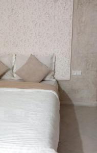 sypialnia z łóżkiem z białą pościelą i poduszkami w obiekcie Rachid villa w mieście As-Suwajra