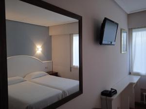 Hotel Sablón في يانس: مرآة تعكس غرفة نوم مع سرير وتلفزيون