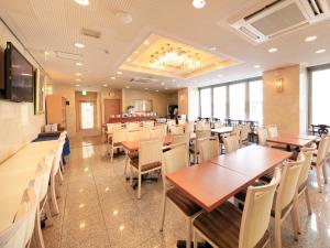 Centurion Hotel Hamamatsu في هاماماتسو: غرفة طعام مع طاولات وكراسي خشبية