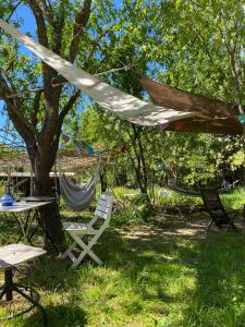 una hamaca, una mesa y sillas bajo un árbol en Yourte à La Campagnette, en Montpellier
