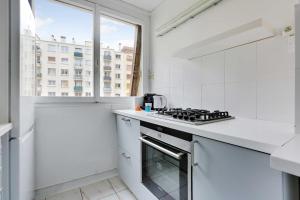 a white kitchen with a stove top oven next to a window at Havre de paix à Porte de Versailles in Paris