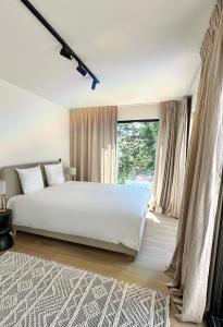 una camera da letto con un grande letto bianco e una finestra di Luxury Apartment with Cosy Garden! a Gand