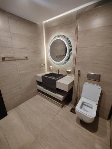 ein Badezimmer mit einem Waschbecken, einem WC und einem Spiegel in der Unterkunft Gold Crest Apartments - DHA P4 in Lahore