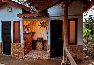 a small house with a door and a stone fireplace at Tropical Jungle Hut in Bukit Lawang