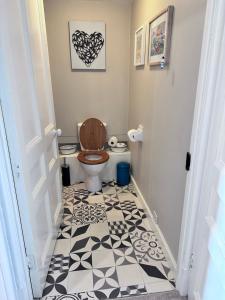 a bathroom with a toilet and a black and white floor at Unique apartment in stunning Manor house in Potterne