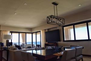 een woonkamer met een tafel en stoelen en een televisie bij Beachfront 2 Bdrm Condo in Exclusive Diamante Golf in Cabo San Lucas