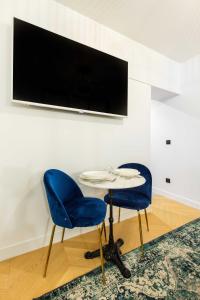2 blaue Stühle und ein Tisch mit einem TV an der Wand in der Unterkunft Chic Apartment in the Prestigious Saint Honoré in Paris