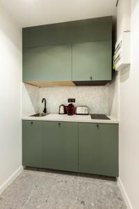 a kitchen with green cabinets and a sink at Chic Apartment in the Prestigious Saint Honoré in Paris