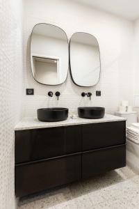 a bathroom with two sinks and two mirrors at Chic Apartment in the Prestigious Saint Honoré in Paris