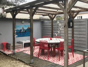 a picnic table and chairs under a wooden pergola at Chambre dorée in Pleurtuit