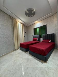 1 Schlafzimmer mit 2 Betten mit roter Bettwäsche und einer Decke in der Unterkunft Magnifique appartement in Derroua