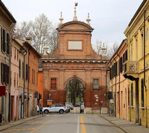 an old brick building with a gate in a street at Una Notte al Museo in Ferrara