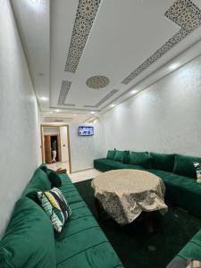 ein Wohnzimmer mit einem grünen Sofa und einem Tisch in der Unterkunft Magnifique appartement in Derroua