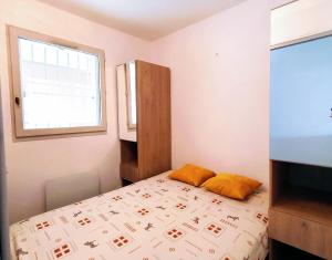 una piccola camera da letto con un letto e una finestra di Le MARTY 9 Vue Mer Loggia Climatisé Piscine Centre a Sète Altre 6 foto