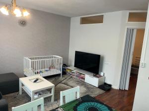 ein Wohnzimmer mit einem Kinderbett, einem TV und einem Babybett in der Unterkunft Siisti ja kodikas asunnon keskustassa+free parking in Kuopio