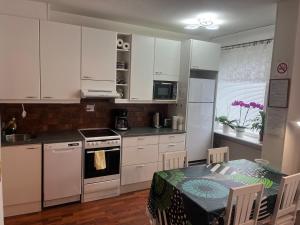 a kitchen with white cabinets and a table and a dining room at Siisti ja kodikas asunnon keskustassa+free parking in Kuopio