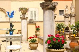 un patio con flores, mesa y sillas en Palazzo Aurora, en Alezio
