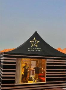 a black tent with two men standing in a window at RUM SUNRlSE LUXURY CAMP in Wadi Rum