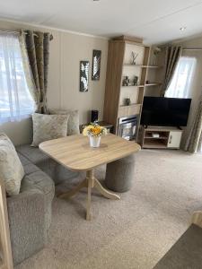 ein Wohnzimmer mit einem Tisch, einem Sofa und einem TV in der Unterkunft Lakeside Escape Modern 2 Bedroom Holiday Home in Overstone